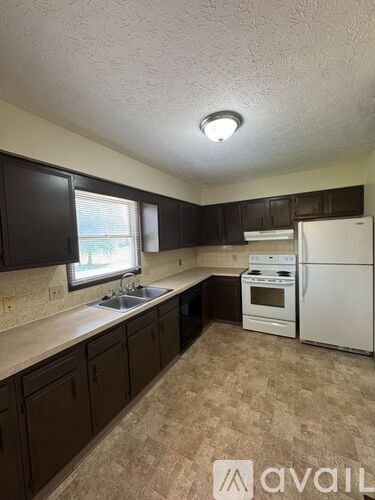 A kitchen with brown cabinets and white appliances.