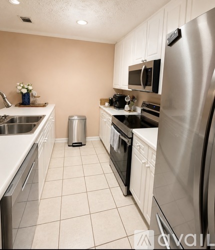 A kitchen with white cabinets and a stainless steel refrigerator.