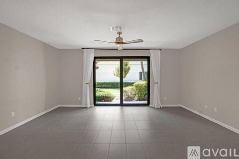 A spacious room with a ceiling fan and sliding glass doors leading to a garden.