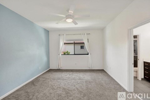 A room with a ceiling fan and a window with a view of a building.