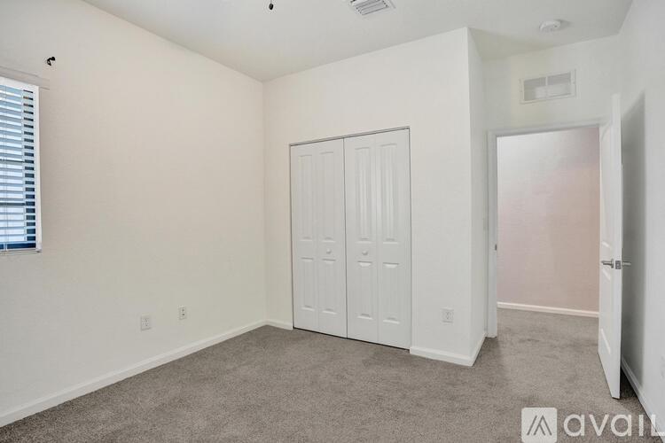 A bedroom with a white closet and carpeted floor.