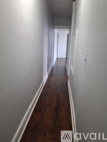 A long hallway with wood floors and white walls.
