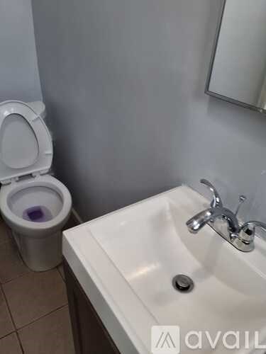 A white sink with a silver faucet is next to a toilet in a bathroom.