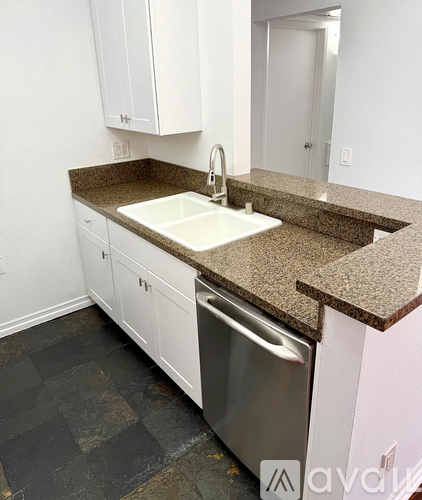 A kitchen with a granite counter top and white cabinets.