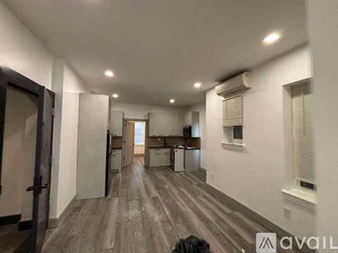 A spacious room with wooden floors and white walls.