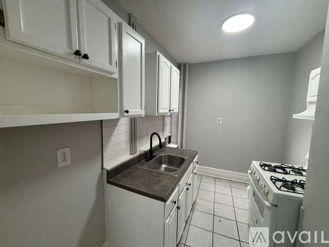 A kitchen with white cabinets and a black countertop.