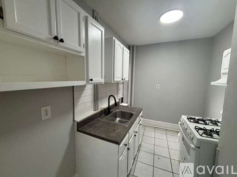 A kitchen with white cabinets and a black countertop.