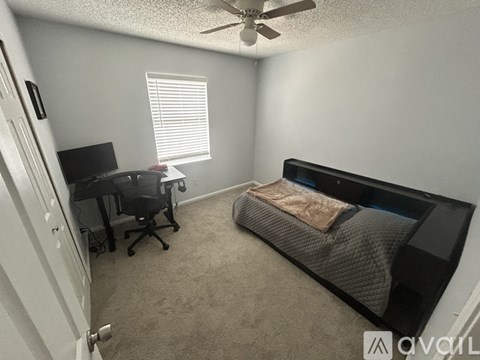 A bedroom with a bed, desk, and chair.