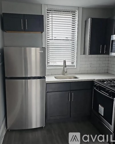 A modern kitchen with a stainless steel refrigerator and black cabinets.