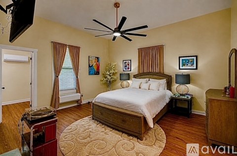 A bedroom with a bed, dresser, and ceiling fan.