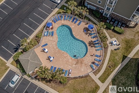 An aerial view of a pool surrounded by a brick border with chairs around it.