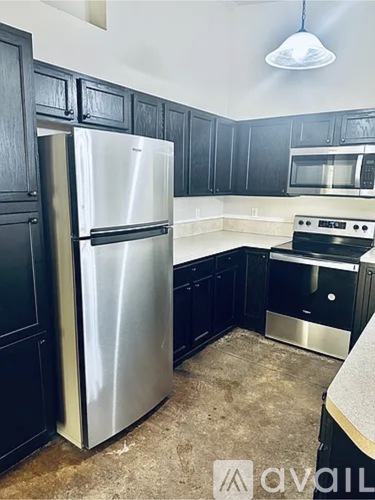 A kitchen with black cabinets and a stainless steel refrigerator.