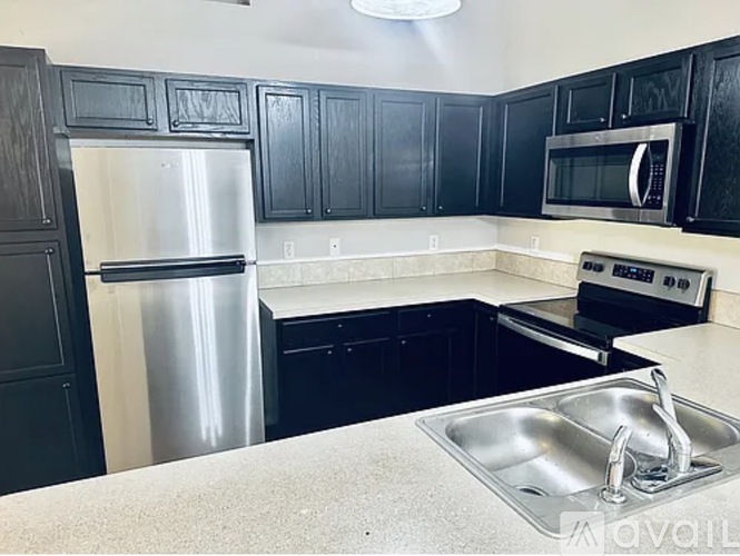 A kitchen with black cabinets and a stainless steel refrigerator.