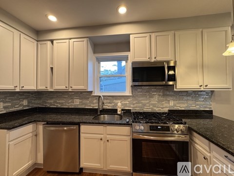 A kitchen with white cabinets and black countertops.
