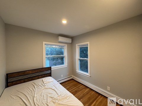 A bedroom with a bed, a window, and a wall-mounted air conditioner.