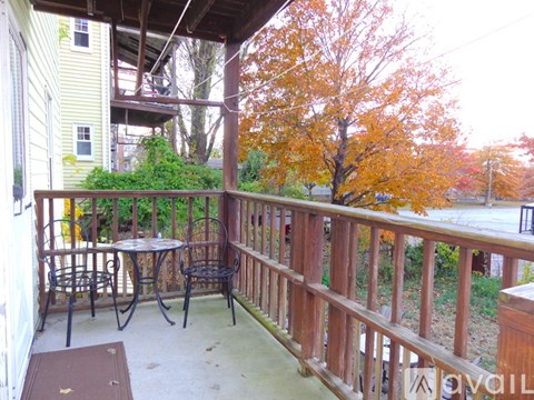 A balcony with a table and chairs overlooking a tree.