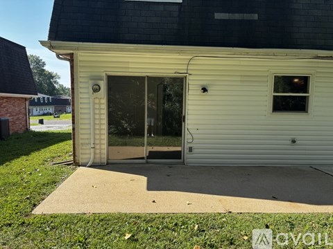 A small white building with a black roof and a glass door.