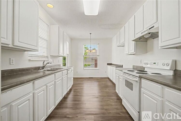 A kitchen with white cabinets and a wooden floor.