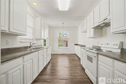 A kitchen with white cabinets and a wooden floor.