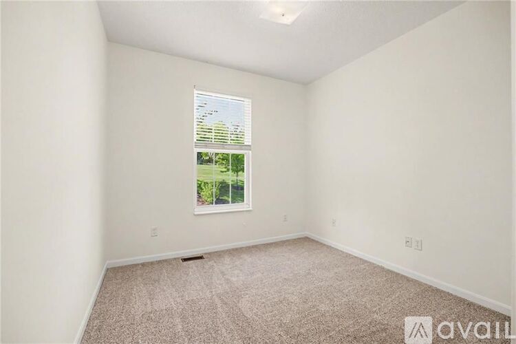 A room with a carpeted floor and a window showing a view of trees and a building.