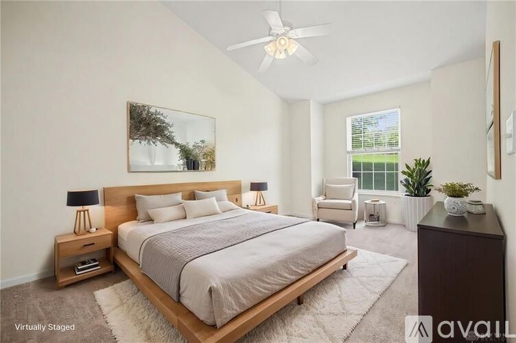 A bedroom with a large bed, a ceiling fan, and a painting on the wall.