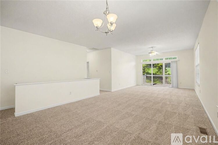 A spacious room with carpeted floor and a chandelier hanging from the ceiling.