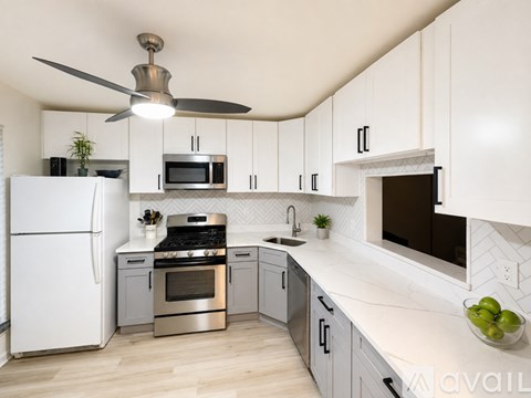 A modern kitchen with white cabinets and stainless steel appliances.