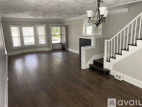 A large open room with wooden floors and a staircase on the right side.