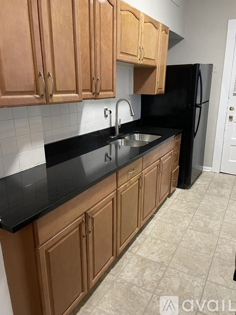 A kitchen with wooden cabinets and a black refrigerator.