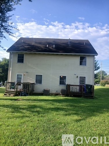 A white house with a black roof and a porch.