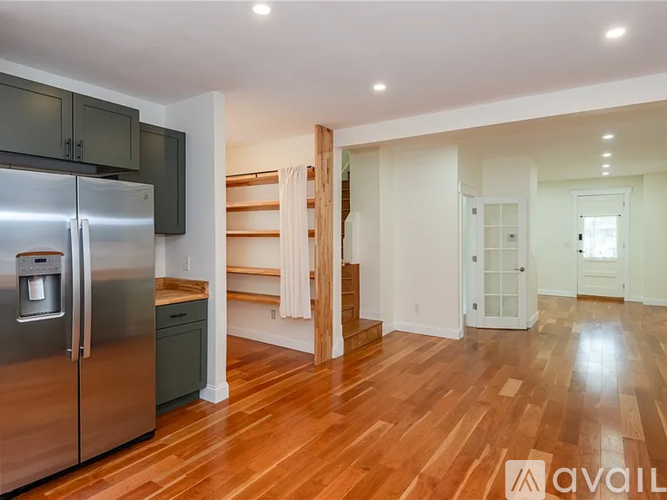 A kitchen with a stainless steel refrigerator and wooden floors.