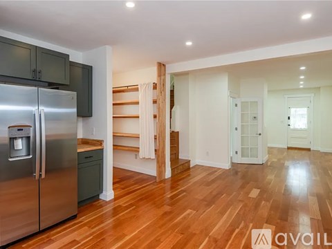 A kitchen with a stainless steel refrigerator and wooden floors.