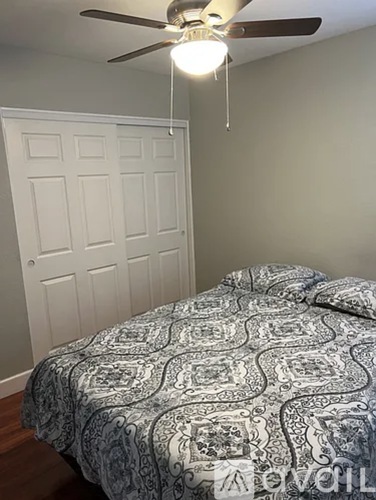 A bedroom with a bed and a ceiling fan.