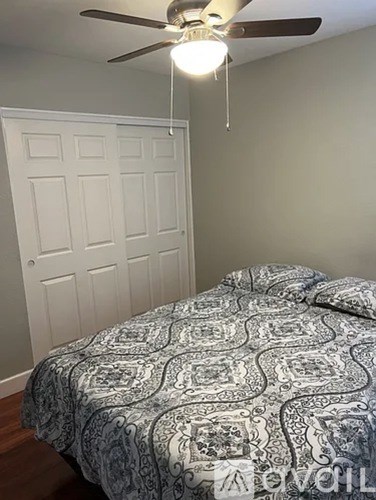 A bedroom with a bed and a ceiling fan.