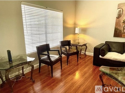 A living room with a glass table and a black couch.