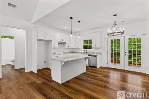 A kitchen with white cabinets and a wooden floor.