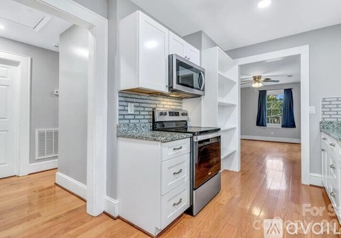 A kitchen with white cabinets and a microwave above the stove.