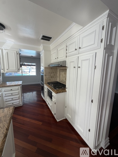 A kitchen with white cabinets and a wooden floor.