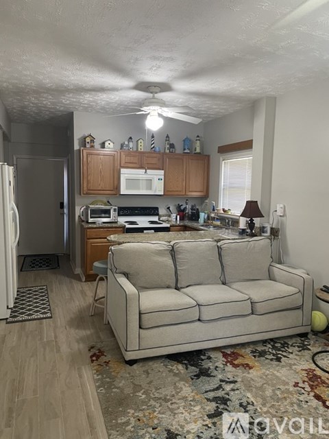 A kitchen with a refrigerator, microwave, oven, and a couch.