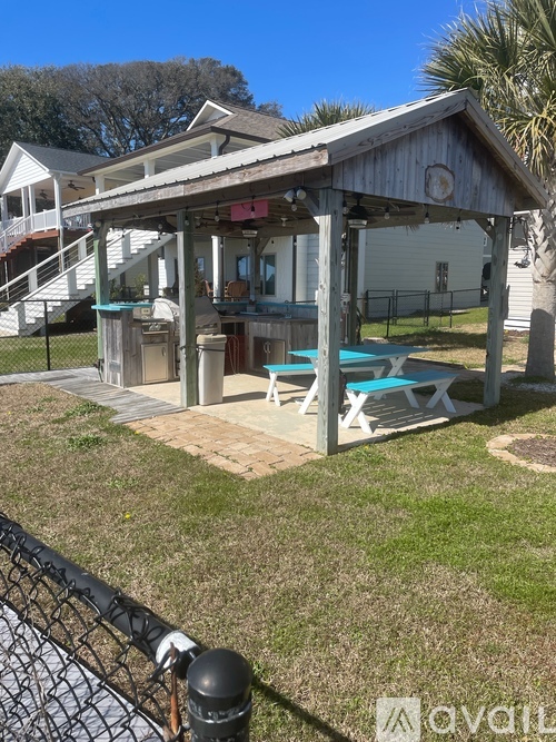 A gazebo with a white roof and a blue bench is in the foreground.