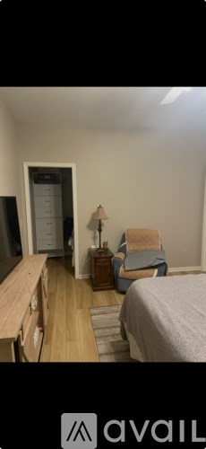 A bedroom with a bed, chair, and lamp.
