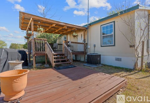 A wooden deck with a large orange pot and a small tree in front of a house.