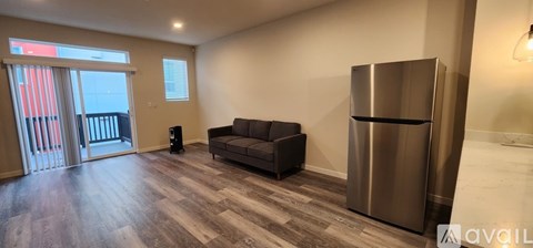 A living room with a couch, a refrigerator, and a speaker.