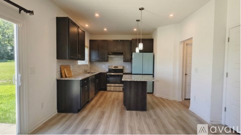 A kitchen with black cabinets and a wooden floor.