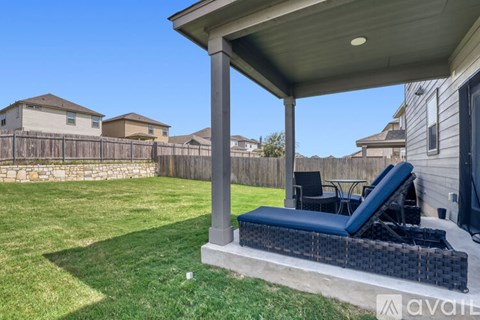A backyard with a hot tub and a covered patio area.