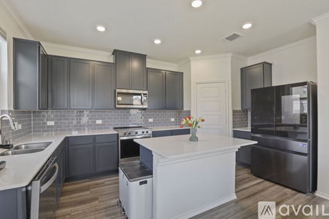 A modern kitchen with dark grey cabinets and a white island.