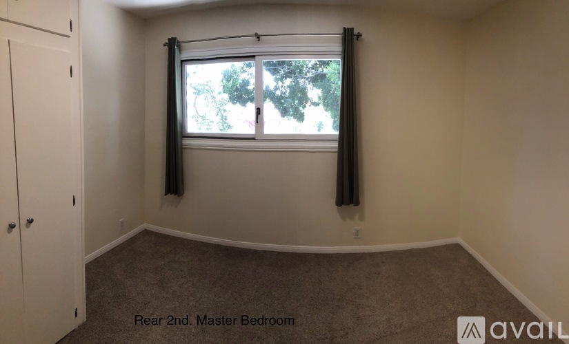 A bedroom with a window and a carpeted floor.
