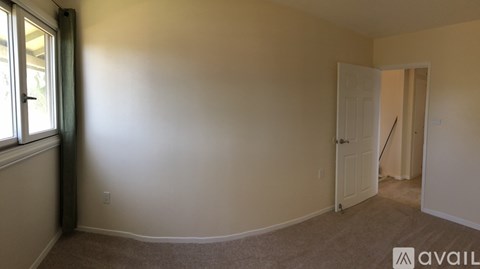A room with a carpeted floor and a door on the right side.