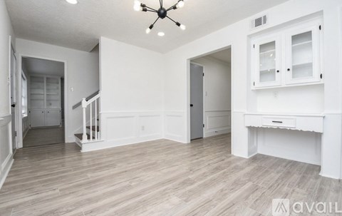 A spacious room with a white desk and a ceiling fan.