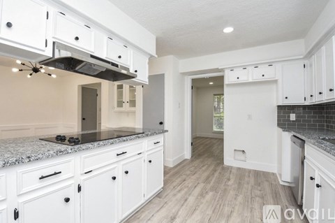A kitchen with white cabinets and a granite countertop.